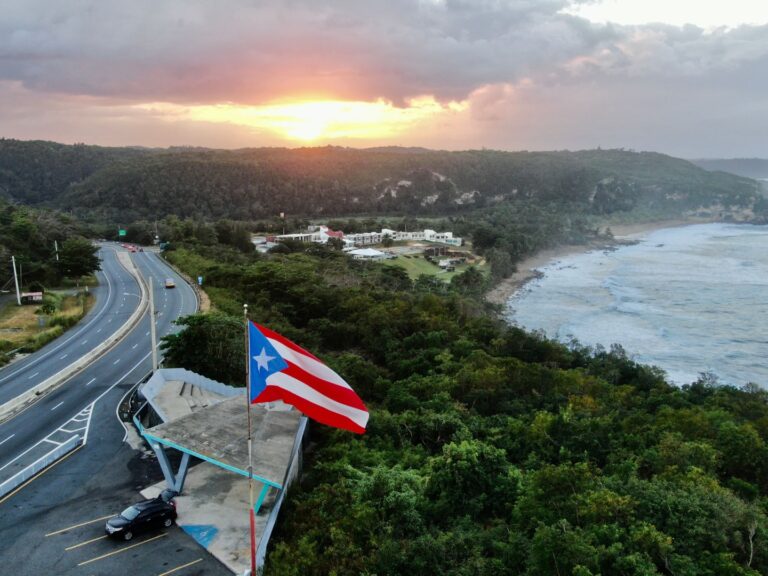 An aerial shot of the Flag of Puerto Rico waving in the air at a golden sunset in Quebradillas